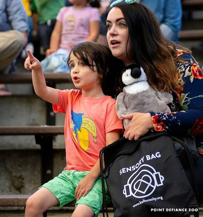 Child pointing at a show beside a woman holding a Point Defiance Zoo sensory bag