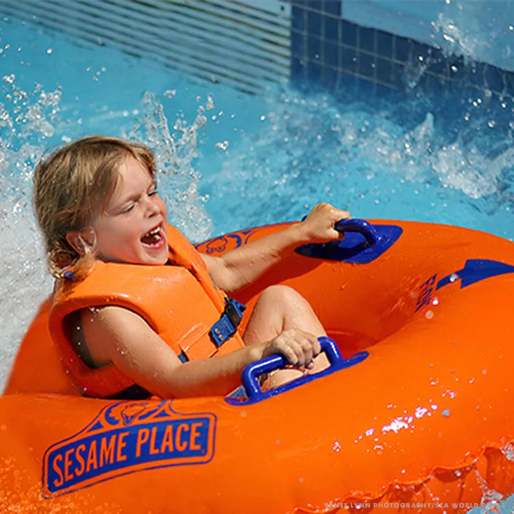 Laughing child riding an orange tube down a water slide at Sesame Place