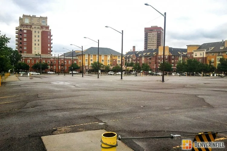 Empty surface parking lot in downtown Denver with apartment buildings beyond