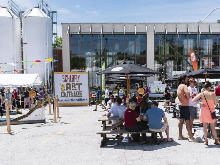 Visitors at picnic tables outside a brewery during the Schlafly Art Outside festival in St. Louis