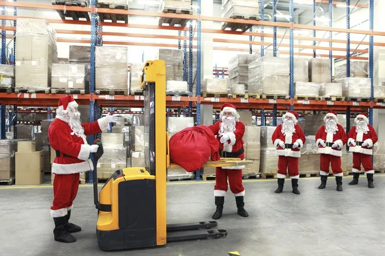 Seasonal workers dressed as Santa Claus in a warehouse with a pallet lift and gift sack