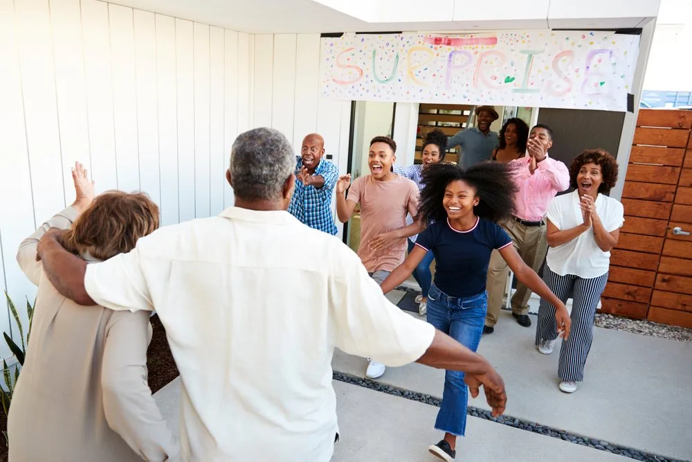 Family running out of a house to hug grandparents at a surprise party