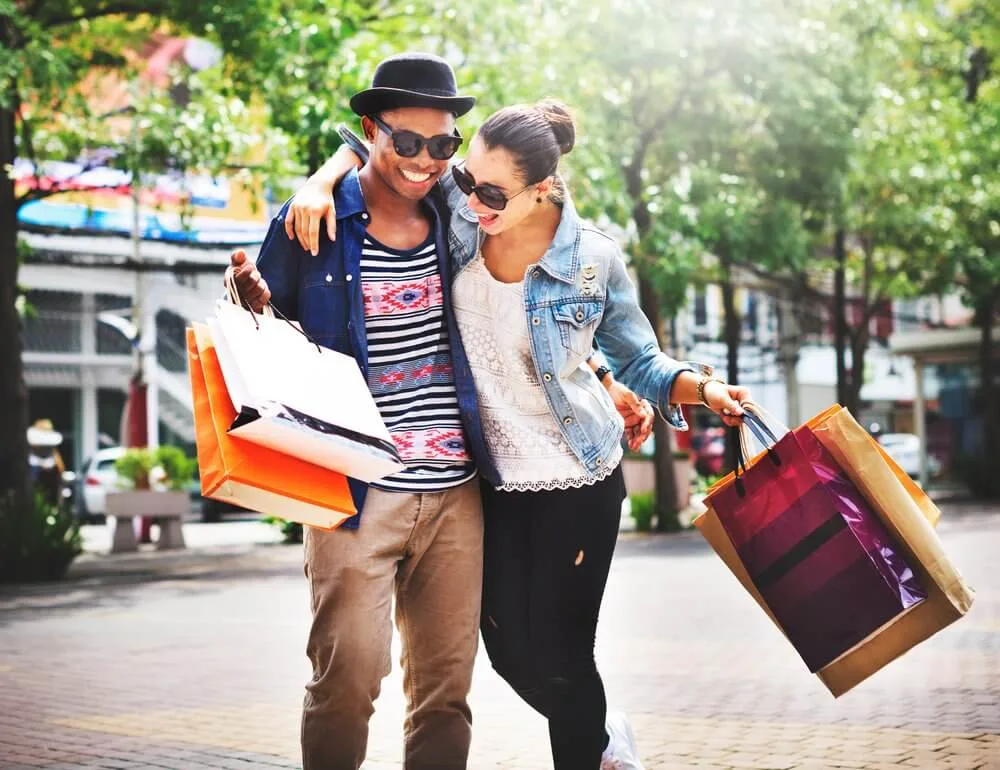 Smiling couple walking arm in arm carrying shopping bags