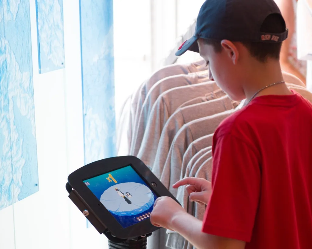 Boy playing the Stay On The Ice tablet game in the Antarctica: Empire of the Penguin gift shop at SeaWorld Orlando