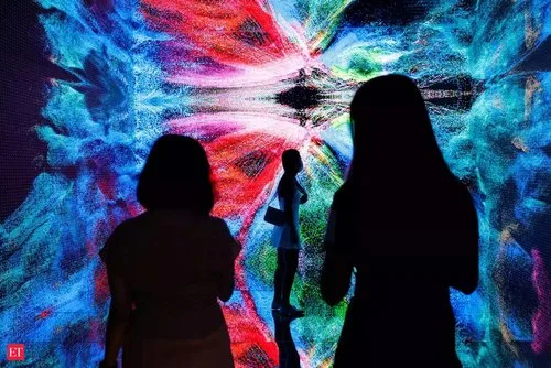 Silhouetted visitors standing before a vivid, swirling digital art projection