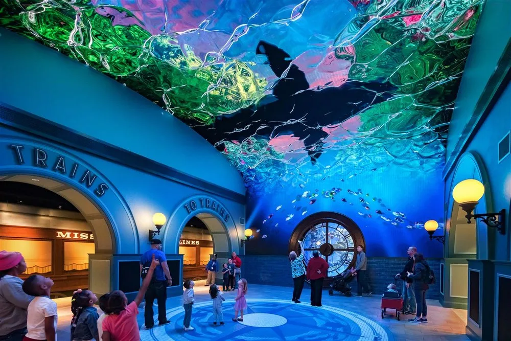 Visitors in the Grand Lobby of St. Louis Aquarium at Union Station beneath a ceiling LED screen of swimming rays