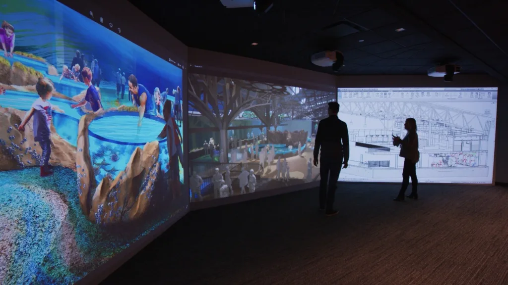 Two people viewing wraparound project renderings in PGAV's Hive immersive virtual environment