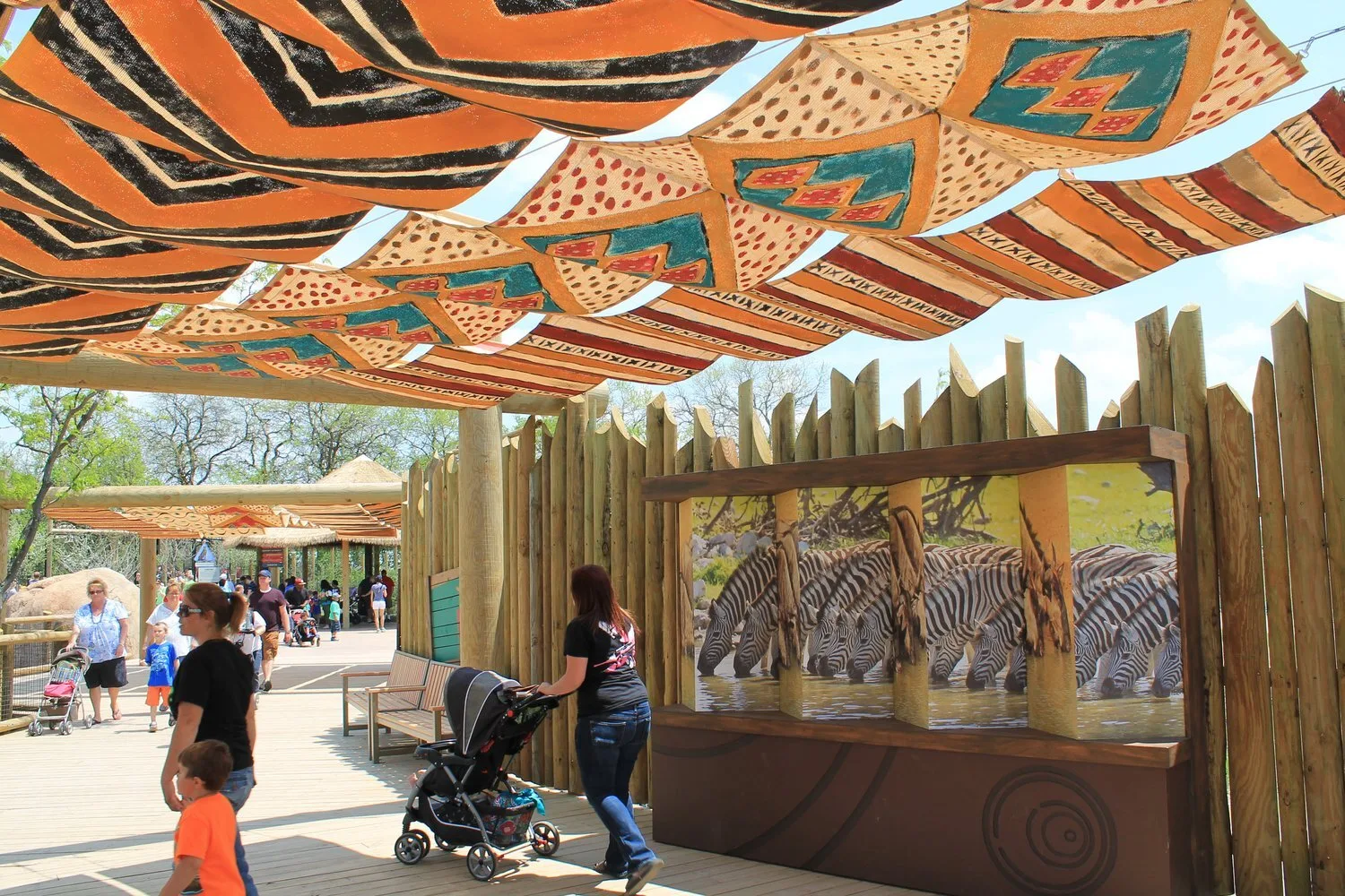 Families with strollers walking under patterned shade sails at CZA's Heart of Africa exhibit