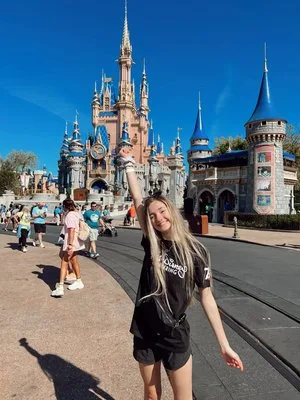 Young woman posing with raised arm in front of Cinderella Castle at Magic Kingdom