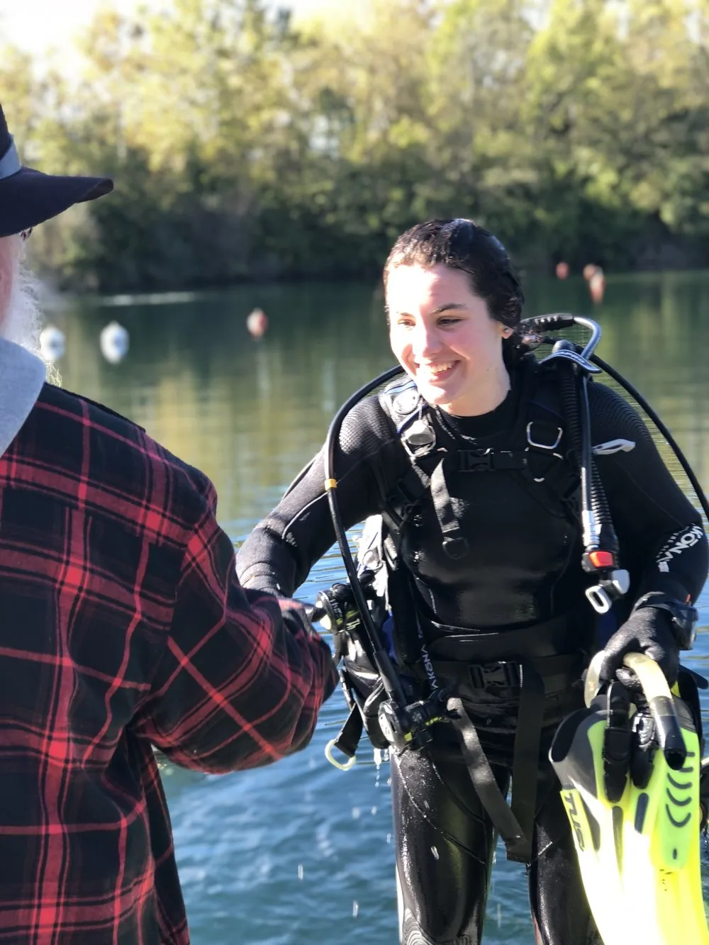 Lizzy Calvert smiling in scuba gear as she climbs out of a lake
