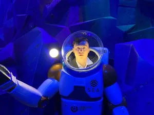 Visitor posing inside a deep-sea diving suit photo op lit in blue