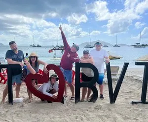 Friends posing with giant I heart BVI letters on a beach in the British Virgin Islands