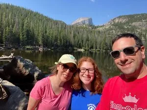Three smiling hikers at a mountain lake near Estes Park, Colorado