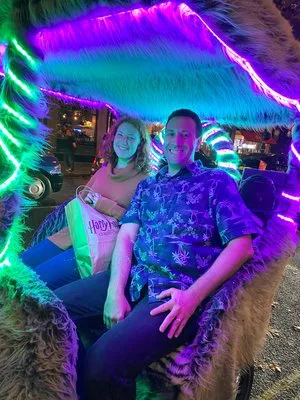 Two guests seated in a neon-lit, fur-covered booth at a themed venue