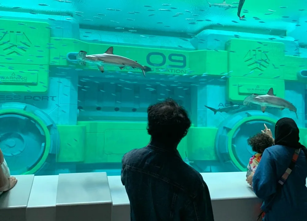 Visitors watching sharks swim past the submerged Seabase structure in Endless Ocean at SeaWorld Abu Dhabi