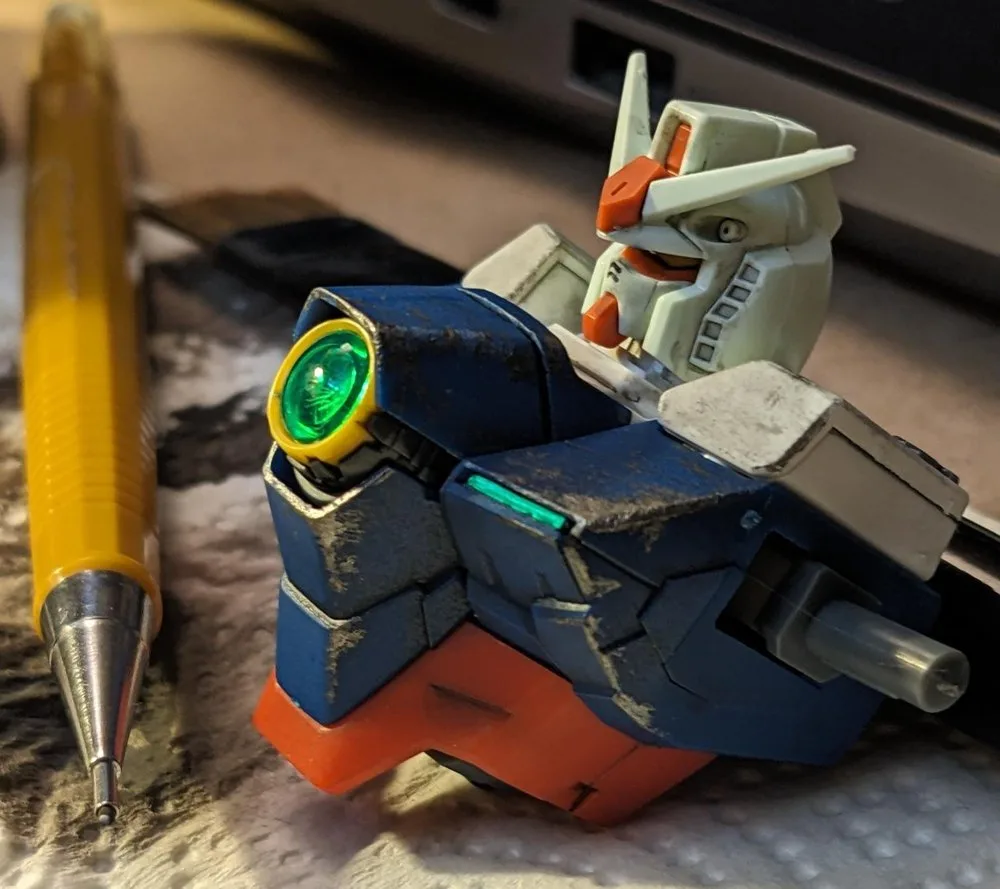 Weathered robot model beside a pencil, showing aging details that add realism