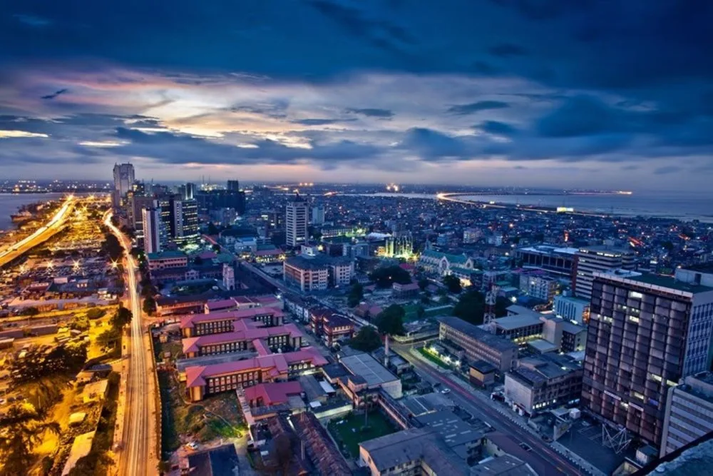 Aerial view of Lagos, Nigeria at dusk with city lights, high-rises and the coastline