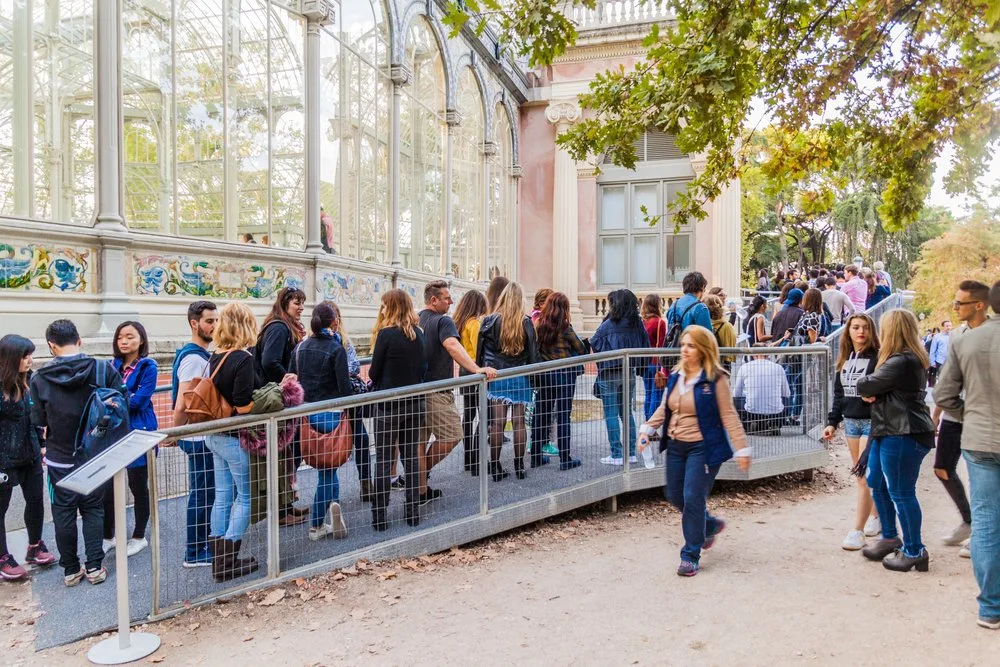 Tourists waiting in a long line outside the Palacio de Cristal in Madrid's Retiro Park