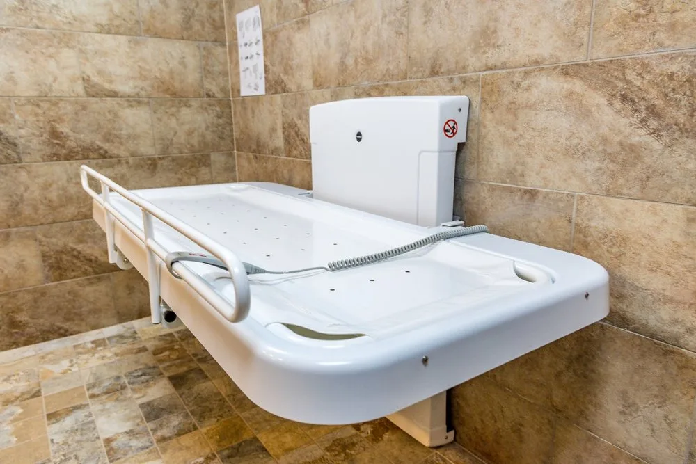 Wall-mounted adult changing table in a tiled accessible restroom