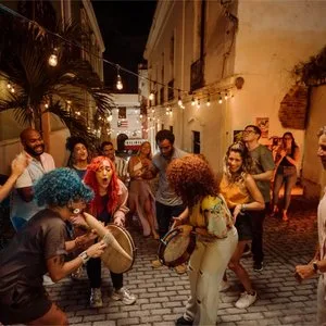 Drummers and dancers celebrating in a lantern-lit cobblestone street at night