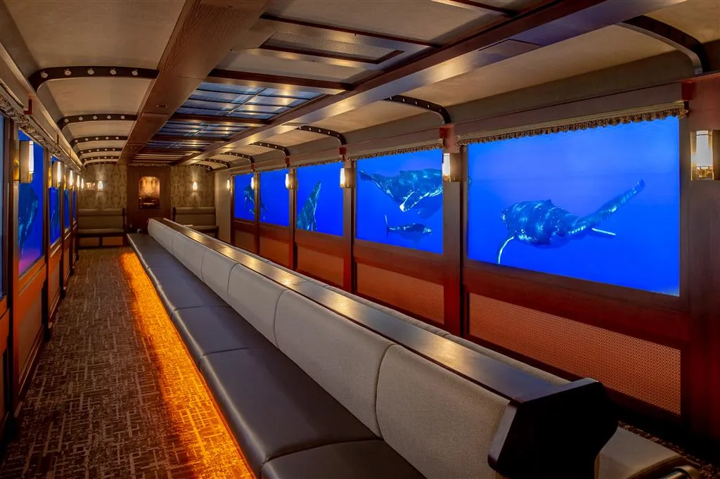 Interior of the replica passenger rail car where video windows show whales during the virtual train ride to the aquarium