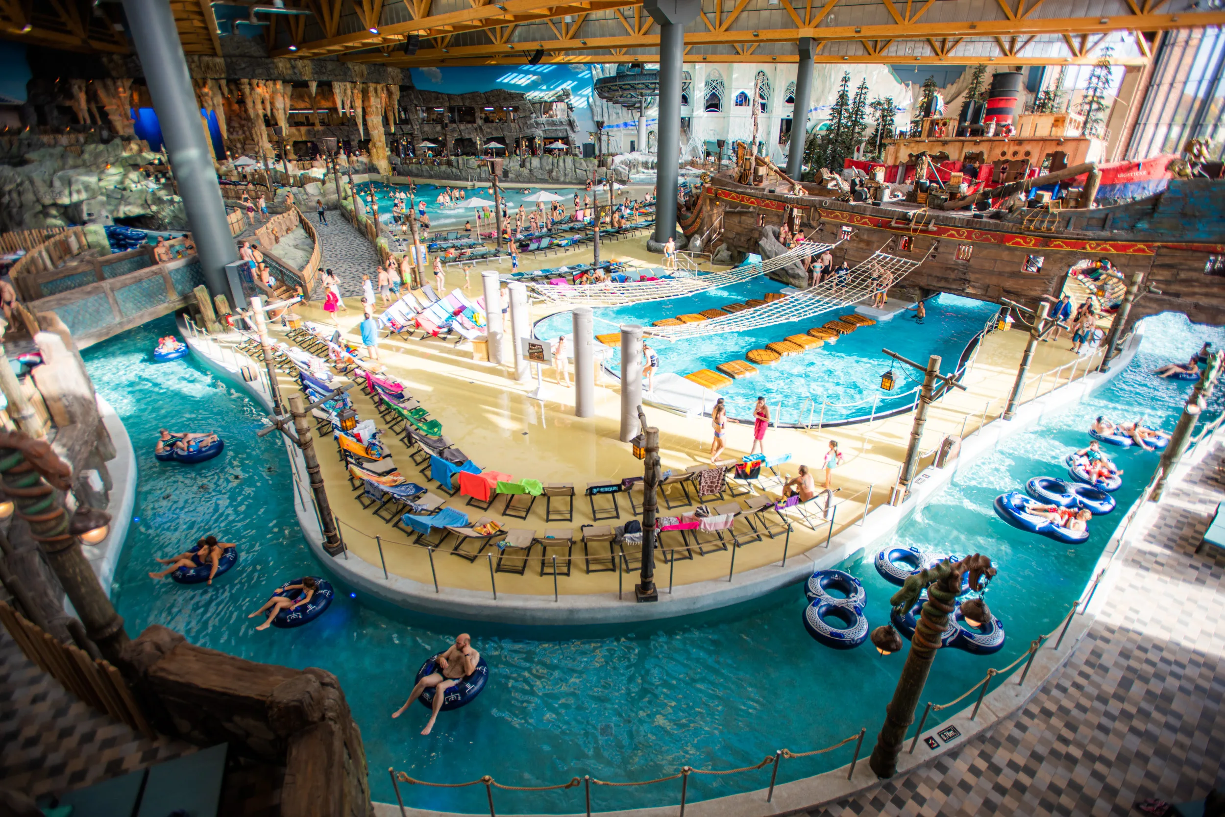 Overhead view of Rulantica indoor water park with a lazy river, tubes, lounge chairs and a pirate ship play area