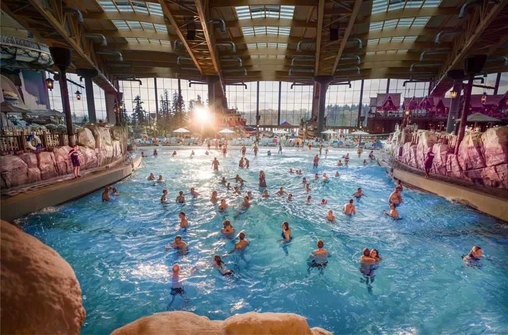 Swimmers fill the Surf Fjord wave pool beneath the timber roof of Rulantica indoor water park at Europa-Park