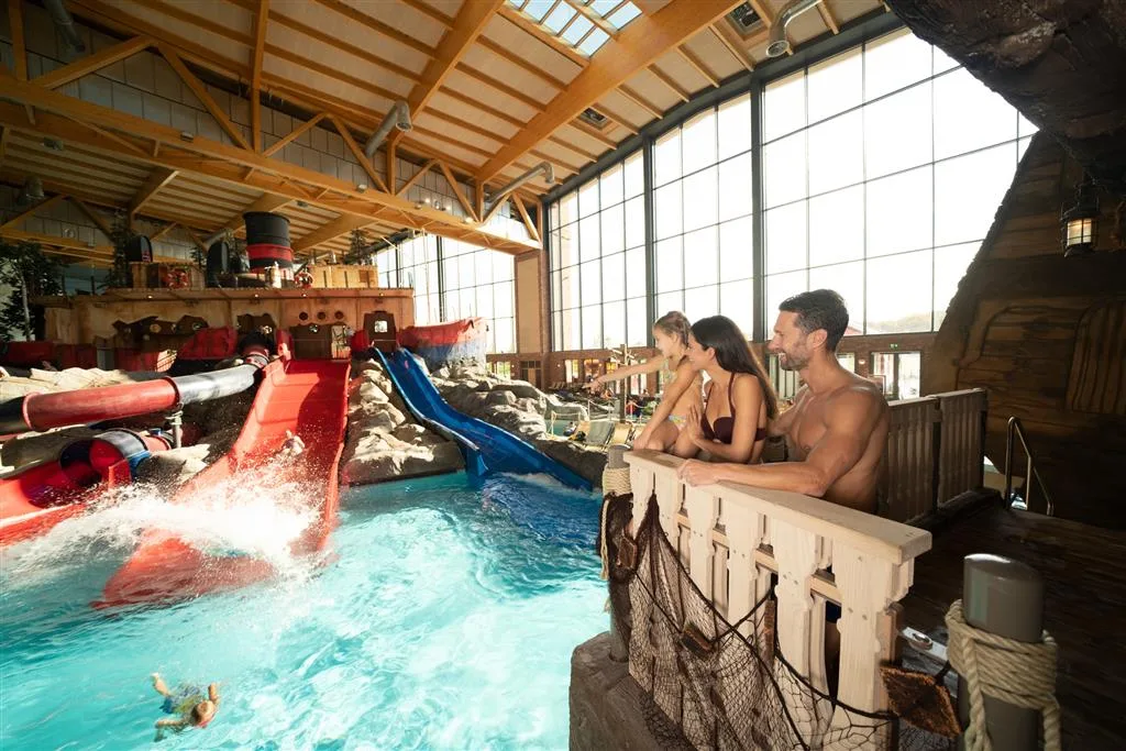 Guests watching from a ship-deck railing as swimmers ride slides into the Skip Strand pool at Rulantica, Europa-Park