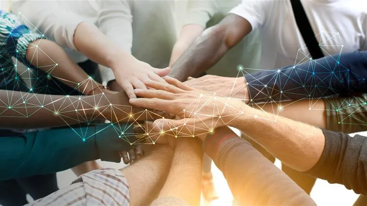Diverse group of hands stacked together in a circle as a sign of teamwork