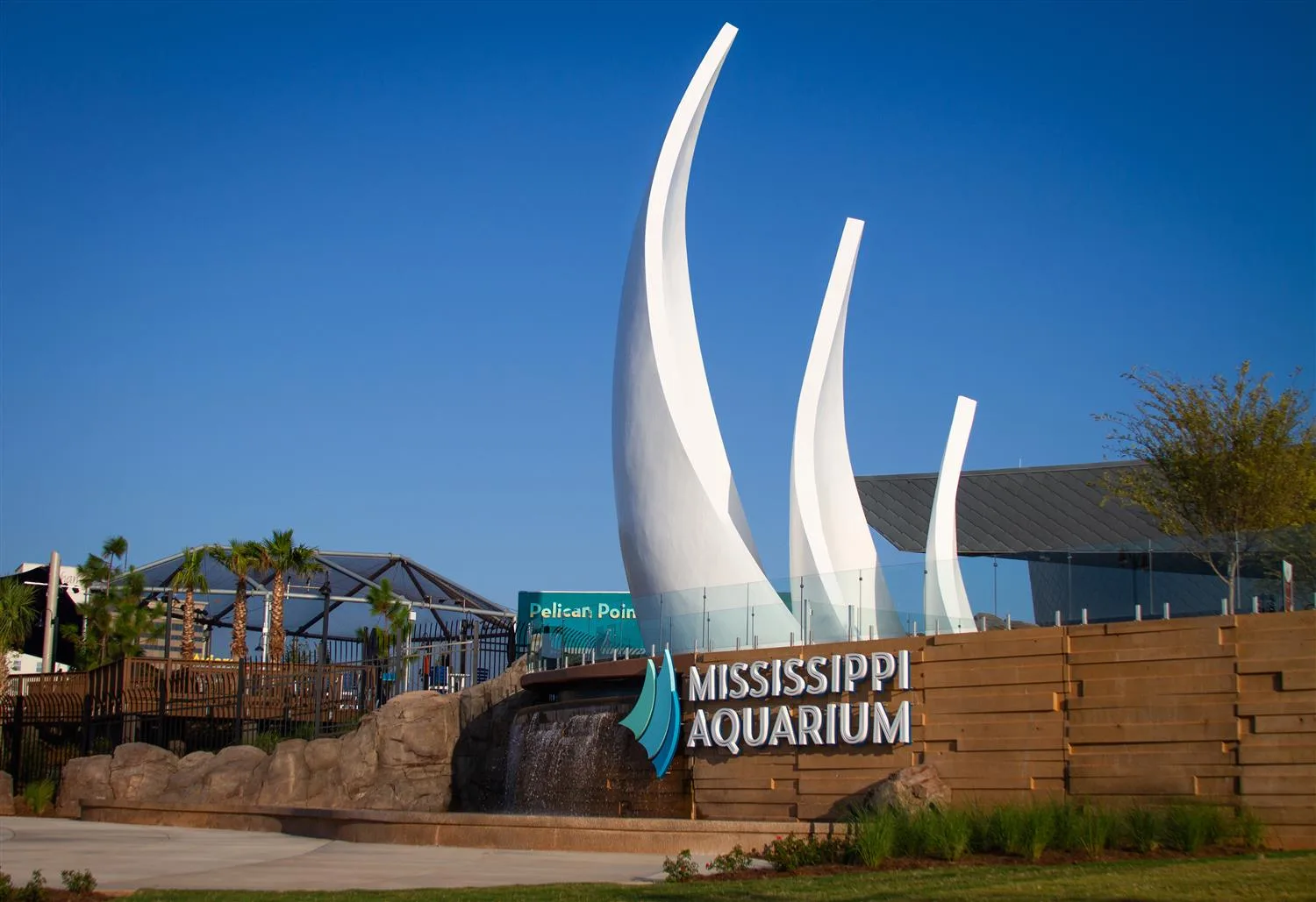 Mississippi Aquarium entrance sign with tall white sail-like sculptures against a blue sky