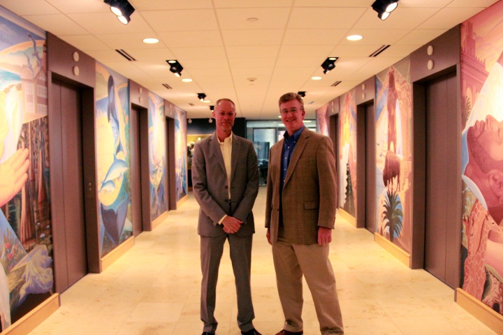 Artist Bryan Haynes and Mike Konzen pose with the new murals in the PGAV Lobby
