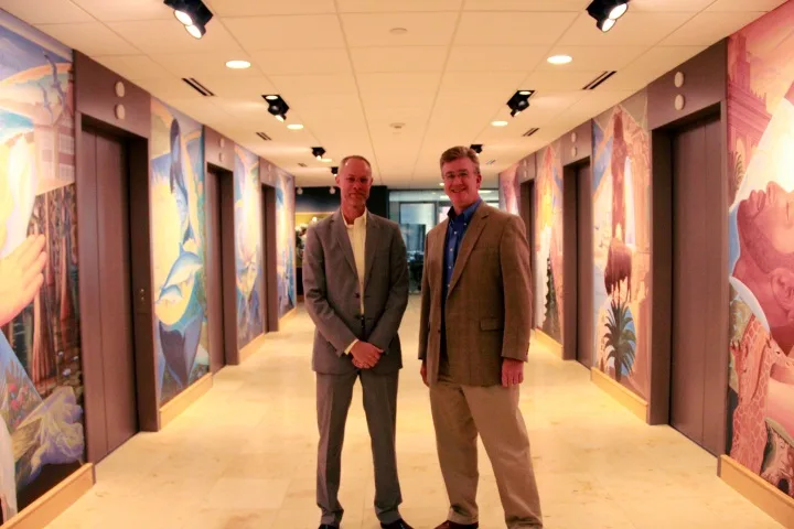Artist Bryan Haynes and Mike Konzen pose with the new murals in the PGAV Lobby