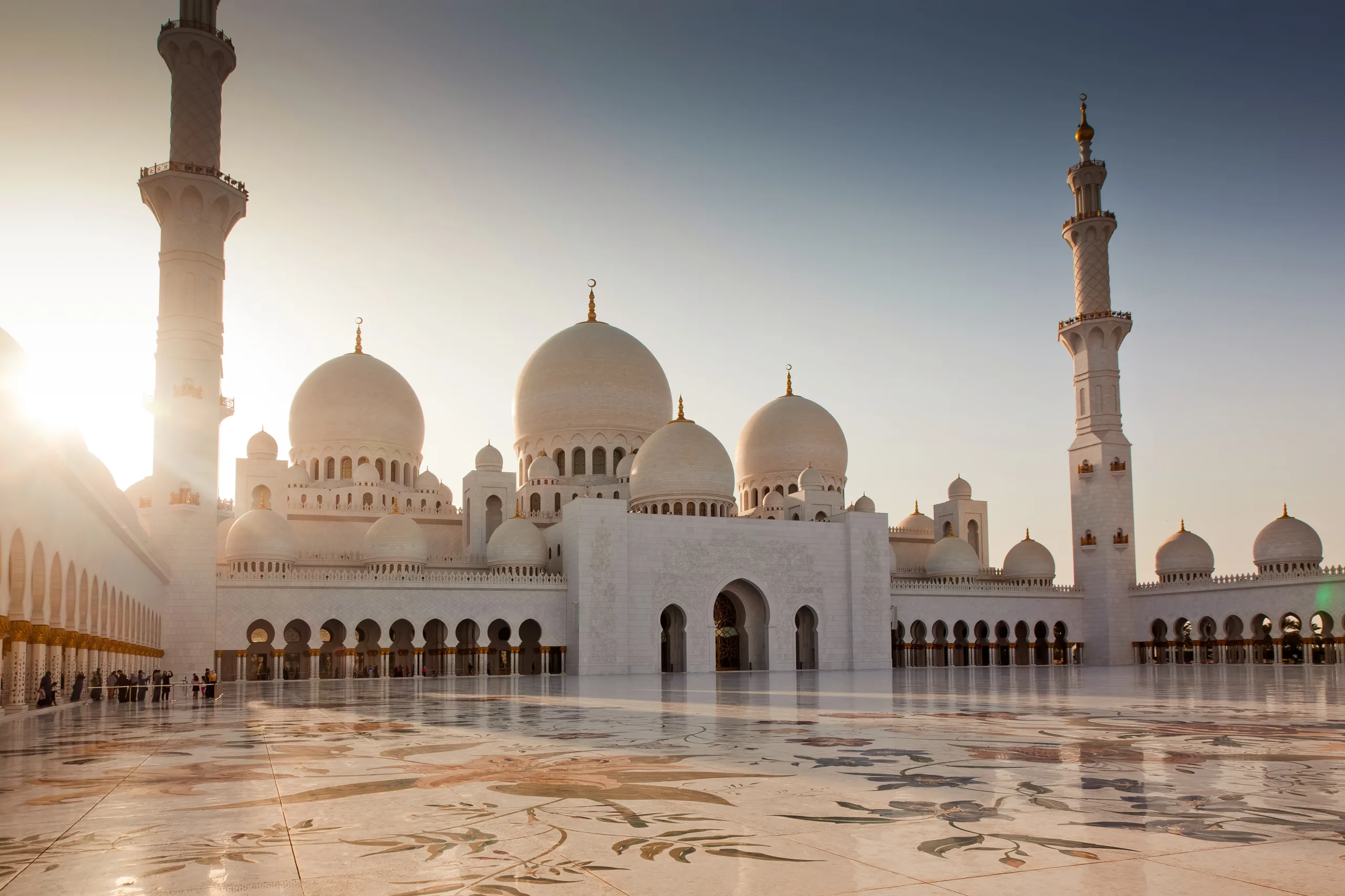 Sheikh Zayed Grand Mosque in Abu Dhabi with white domes and minarets at sunrise