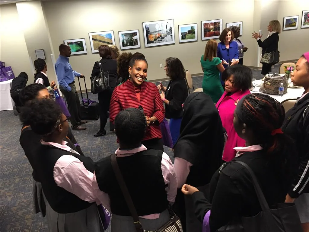 Woman in a red jacket speaking with a circle of students at a networking event