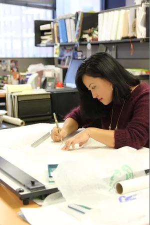 Designer sketching on tracing paper at a drafting desk
