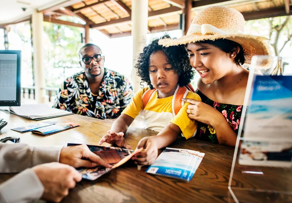 Family checking in at a resort front desk as a staff member hands them brochures