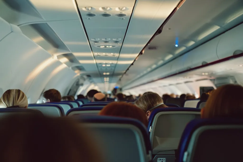 Passengers seated in a full airplane cabin viewed down the aisle