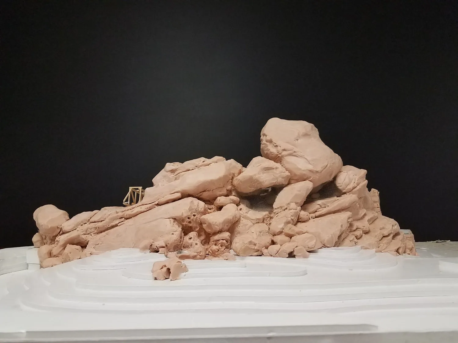 Clay mock-up of a boulder rockwork formation on a white contour model base
