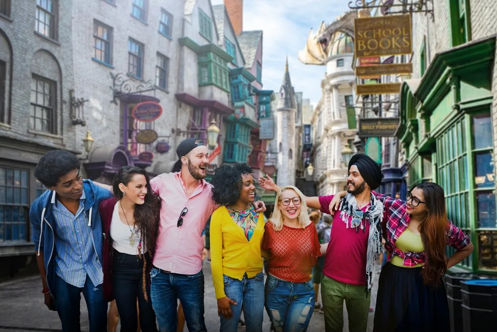 Diverse group of smiling friends posing on a themed village street lined with shop signs