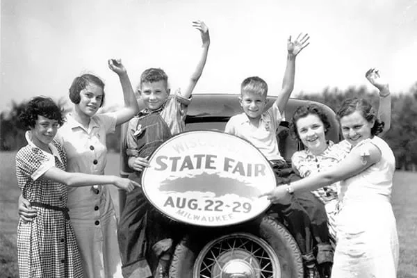 Vintage 1936 photo of kids cheering on a car with a State Fair Aug. 22-29 sign at the Wisconsin State Fair