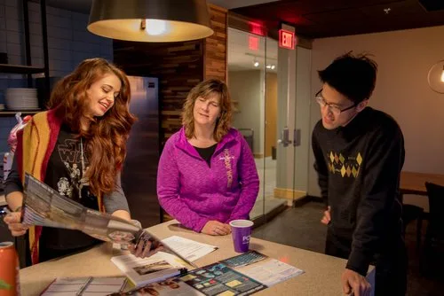 Designers laughing while flipping through magazines for inspiration at an office counter