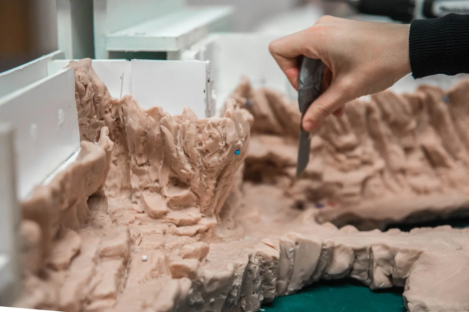 Hand sculpting a clay rockwork model with a carving tool
