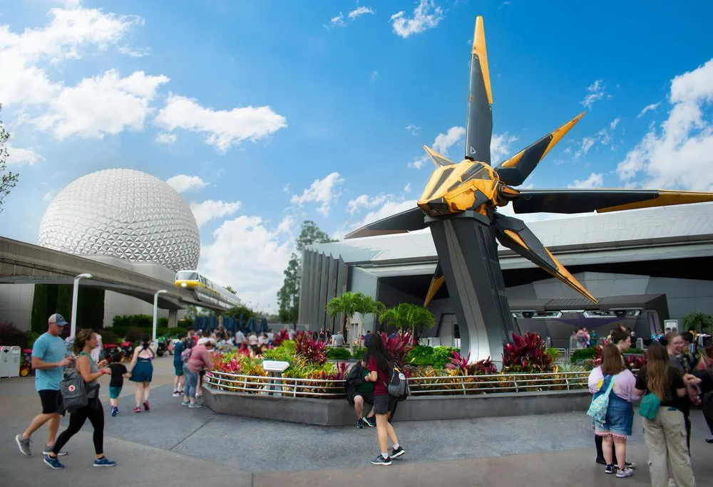 Guests walking past the Guardians of the Galaxy: Cosmic Rewind starship sculpture and Spaceship Earth at EPCOT