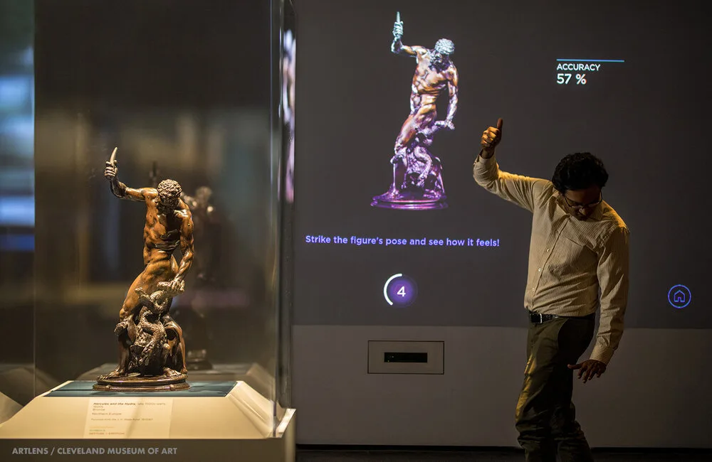 Visitor mimicking a sculpture's pose at a gesture-sensing ArtLens screen at the Cleveland Museum of Art