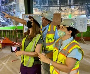 Designers in hard hats and safety vests pointing out details on a construction site walkthrough