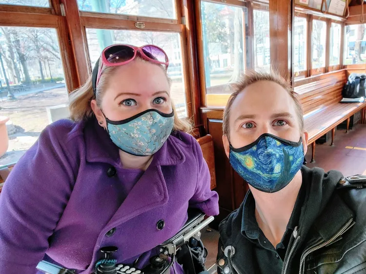 Anna Corbitt of Paraquad and her partner taking a masked selfie aboard a vintage trolley