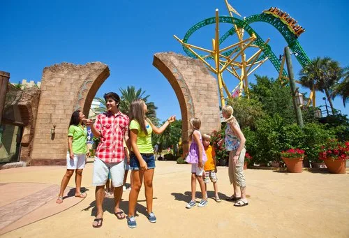 Family standing before stone arches with the Cheetah Hunt coaster track overhead at Busch Gardens Tampa Bay