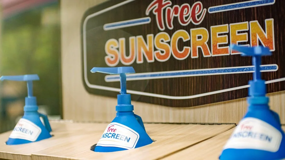 Free sunscreen pump dispensers beneath a Free Sunscreen sign at Holiday World