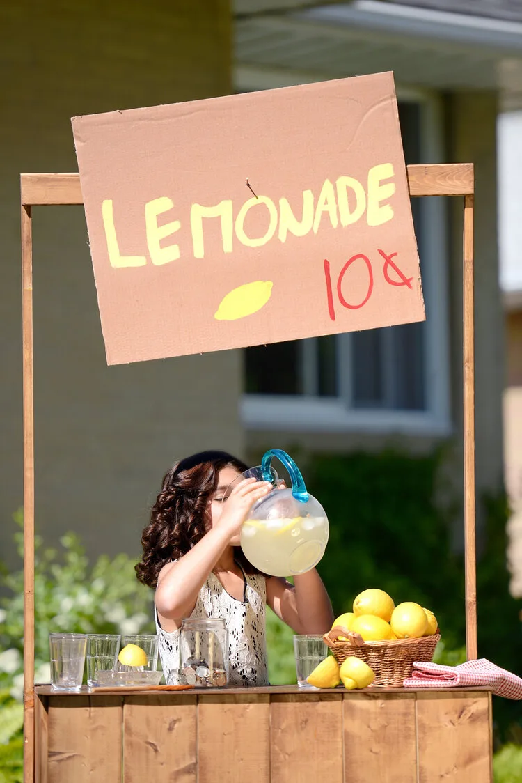 Girl drinking from a pitcher at her own 10-cent lemonade stand
