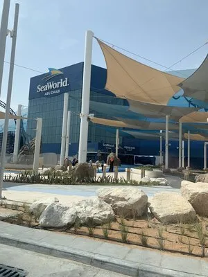 SeaWorld Abu Dhabi entrance building beyond shade sails and rock landscaping